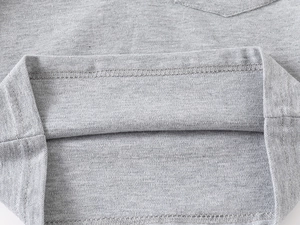 Detail aus grauem Baumwoll-Piqué-Stoff mit flacher Naht an einem Kinder-Poloshirt