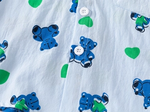 Detail of boys' light blue cotton shirt with bear and heart print and white buttons
