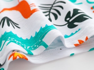 Gros plan du tissu en coton bambou avec imprimé dinosaure et coutures de précision