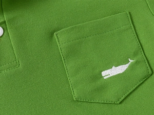 Close-up of green pique polo shirt pocket with white whale embroidery detail