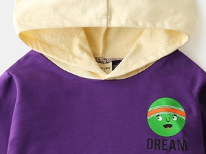Detail of kids hoodie with purple fabric, yellow hood lining and green cartoon print