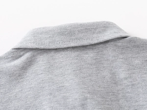 Nahaufnahme der melierten Piqué-Struktur und Kragennaht eines grauen Polo-Shirts für Jungen