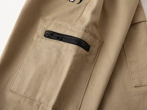 Close-up of khaki cargo pants pocket with durable black zipper and twill fabric detail