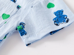 Detail of light blue cotton fabric featuring bear and green heart prints with stitching