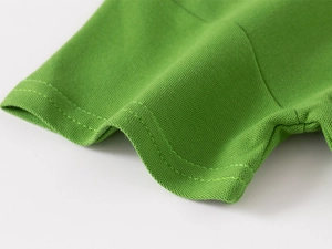 Macro detail of grass green piqué cotton fabric showing fine stitching and premium texture