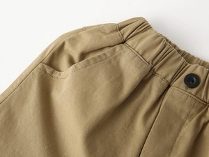 Vue macro de la taille élastique kaki et des broderies sur ce short décontracté garçon