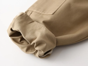Macro detail of khaki twill trousers showing the rolled hem and high-quality stitching