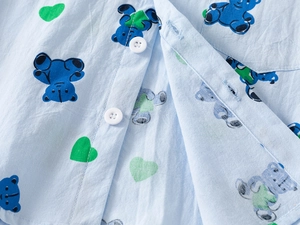 Detail of light blue boys' shirt featuring navy cartoon bear and green heart prints