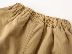 Close-up of elastic waistband on khaki cotton shorts showing premium stitching and fabric