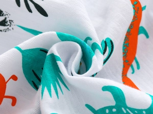Détail du tissu en gaze de coton doux avec motifs de dinosaures et feuilles colorés