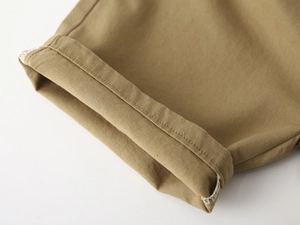 Détail macro du tissu en coton sergé kaki avec double surpiqûre de qualité sur l'ourlet