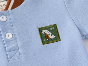 Macro view of blue kids polo shirt featuring breathable piqué fabric and dinosaur embroidery