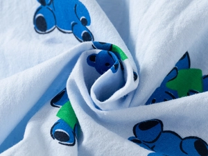 Macro detail of soft light blue cotton fabric with blue cartoon bears and green patterns