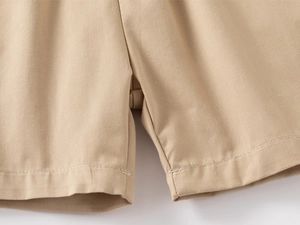 Detail of khaki cotton shorts showing precise white contrast stitching on the hem and crotch