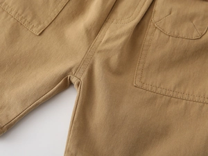 Detailed close-up of khaki cotton twill fabric and sturdy side pocket stitching on boys' shorts