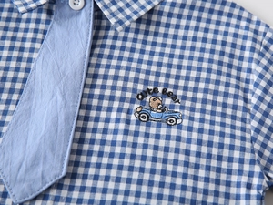Detail of blue plaid boys' shirt featuring cute bear embroidery and matching light blue tie