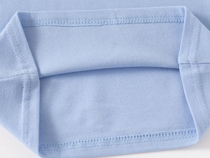 Close-up of light blue piqué cotton fabric showing breathable texture and double stitching