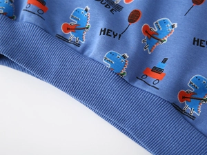 Macro detail of ribbed hem on kids blue sweatshirt with cartoon dinosaur and guitar print