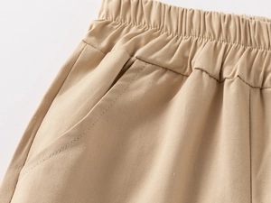 Close-up of boys beige cotton shorts showing elastic waistband and stitching details