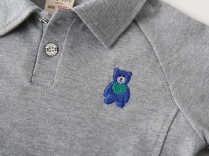 Gros plan du polo gris pour enfant avec broderie ours bleue et col à boutons classique