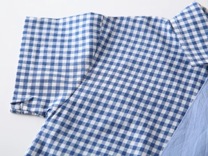 Detailed view of blue and white gingham patterns on a boys short-sleeve shirt
