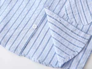 Detail of light blue striped cotton linen shirt showing button and pocket stitching