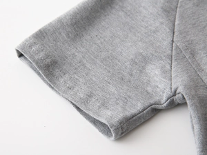 Gros plan d'un polo gris pour enfant montrant le tissu en coton piqué et les coutures