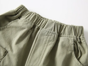 Close-up of boys' green casual shorts featuring elastic waistband and slanted side pockets
