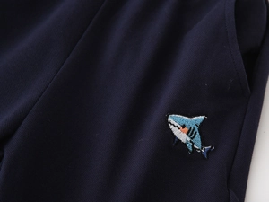 Detail of shark embroidery and breathable mesh fabric on boys navy polo shorts