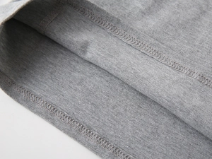 Gros plan détaillé de l'ourlet du polo gris avec coutures soignées et texture de maille