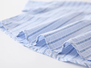 Macro detail of the breathable blue and white striped cotton fabric on a boys' shirt