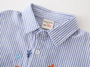 Gros plan détaillé de la chemise rayée pour garçon avec broderies d'étoile de mer et corail