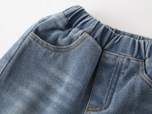 Detail of boys denim jeans showing elastic waistband and orange stitching on blue fabric