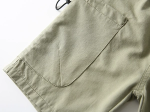 Detailed macro view of olive green cargo shorts featuring high-quality double stitching