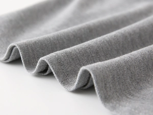 Gros plan sur le tissu en maille grise montrant la texture et l'ourlet à double aiguille