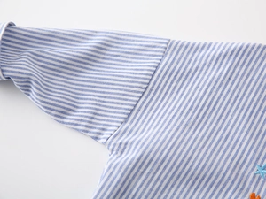 Détail de la chemise en coton à rayures bleues avec broderie fine au thème marin