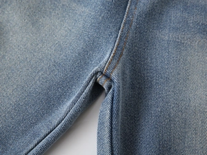 Close-up of blue denim jeans with durable double-needle stitching and yellow thread detail