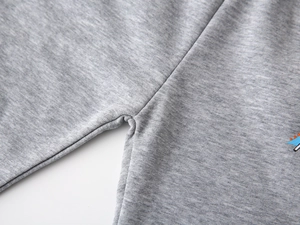 Close-up detail of grey knit cotton fabric featuring a colorful cartoon dinosaur pattern
