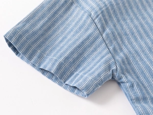 Close-up of the fine stitching and breathable cotton fabric on a blue striped kid shirt
