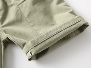 Close-up of olive green cotton shorts showing precise stitching and cuffed hem detail