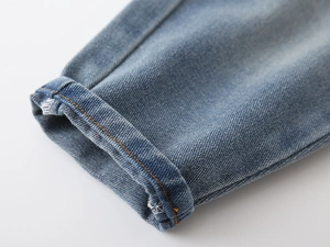 Close-up of blue denim cuff with orange contrast stitching and twill texture detail