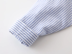 Gros plan du poignet rayé bleu et blanc d'une chemise à manches longues en coton