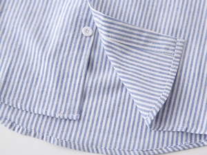 Vue détaillée du tissu en coton à rayures bleues et blanches avec ourlet et bouton