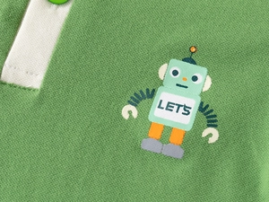 Détail du tissu en coton piqué vert montrant un robot imprimé sur un polo pour garçon