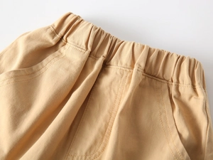 Dettaglio della vita elastica e delle cuciture sui pantaloncini in cotone kaki da bambino