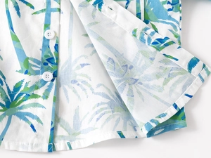 Detail of boys summer shirt featuring tropical coconut tree prints and white buttons