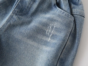 Detail of light blue kids' denim jeans showing pocket stitching and washed cotton texture