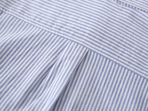 Gros plan des coutures fines sur le pli arrière d'une chemise à rayures bleues