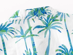 Detail of the V-neck collar and stitching on a white boy's shirt with teal coconut trees