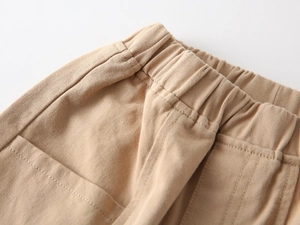 Detail of khaki kids trousers featuring elastic waistband and twill cotton fabric texture